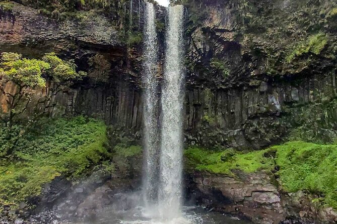 Chania Falls roaring into a green forested volcanic basin