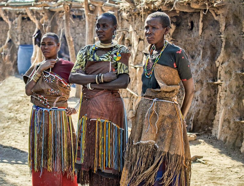 Datooga women scraping and oiling cattle hide leather skirts